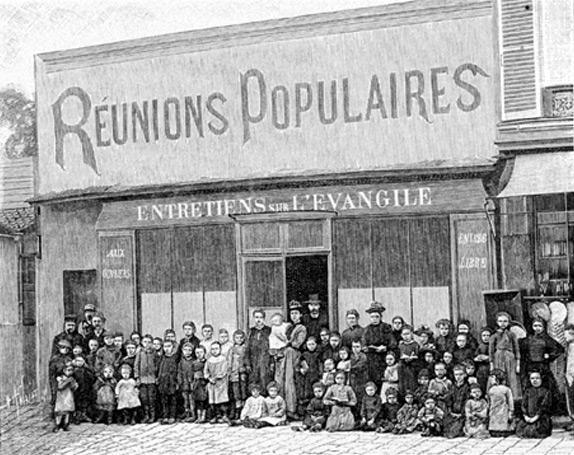 Photo du XIXe en noir et blanc à Paris salle du Faubourg Saint-Antoine un groupe pose devant un batiment dont le fronton dit "réunions populaires, entretiens sur l'évangile"